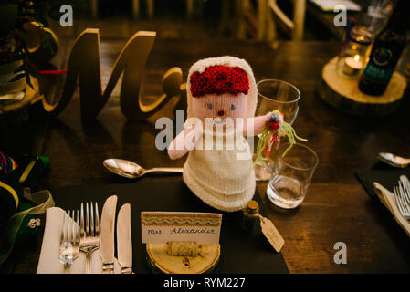 a rustic wooden wedding breakfast table set up with a crochet bride doll Stock Photo
