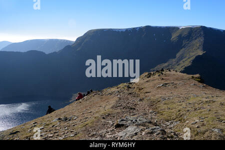 Four Hikers Eating Lunch on the Wainwright Catstycam near Red Tarn, Swirral Edge and Helvellyn in the Lake District National Park, Cumbria, England. Stock Photo