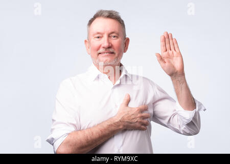 Handsome senior man in white shirt making an oath. Give a promise. Stock Photo