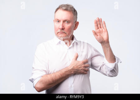 Handsome senior man in white shirt making an oath. Give a promise. Stock Photo