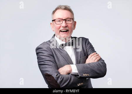 Senior man in suit and glasses looking at camera and laughing on funny joke. Stock Photo