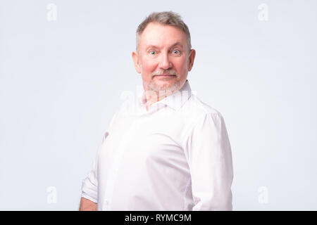 Smiling senior man in white shirt standing and smiling at camera feeling good Stock Photo