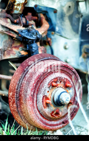 Close up shot of a rusting wheel hub of an abandoned Lincoln Continental car adjacent to a derelict factory building in Pontiac, Michigan, USA. Stock Photo