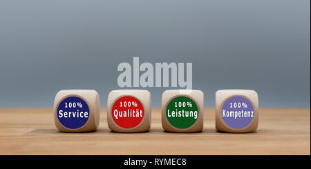 Four cubes with the German text "100% Service", "100% Qualität", "100% Leistung" ,"100% Kompetenz" ("100% Service", "100% Quality", "100% Performance" Stock Photo
