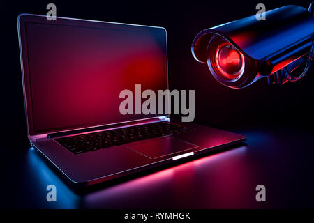 Computer observed by hostile looking camera as a metaphor of stalking or malicious software observing and tracking user. Copy space on laptop screen i Stock Photo