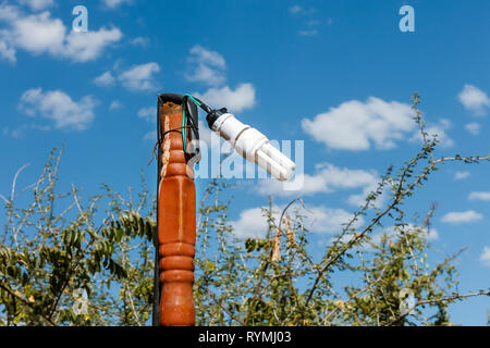 One fluorescent pendant lamp hanging on a pipe against a blue sky Stock Photo