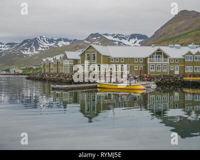 Yellow and white fishing boats at the dock outside the Siglo Hotel along the harbor in Siglufjörður (Siglufjordur) Iceland Stock Photo