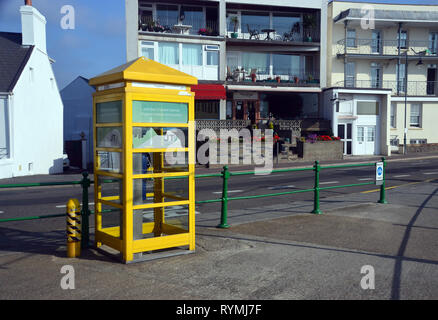 Yellow Phone Box next to the Road on Havre Des Pas in St Helier on the Island of Jersey, Channel Isles, UK. Stock Photo