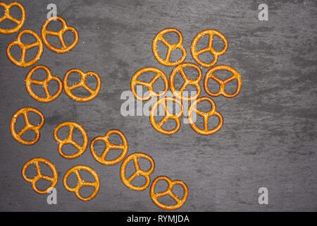 Lot of whole mini salted pretzels flatlay on grey stone Stock Photo