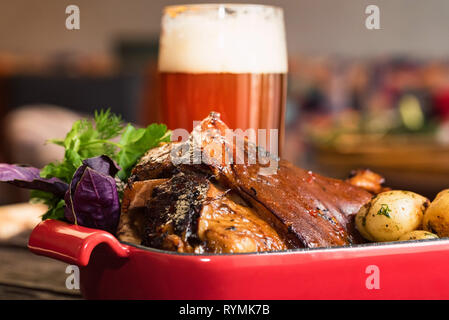 Close up roast pork knuckle served with boiled potatoes and glass of beer Stock Photo