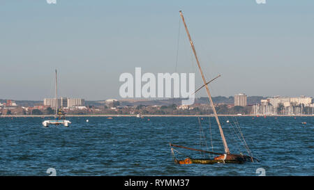 Sailboat sinking into the sea near the coast of Poole, England Stock Photo