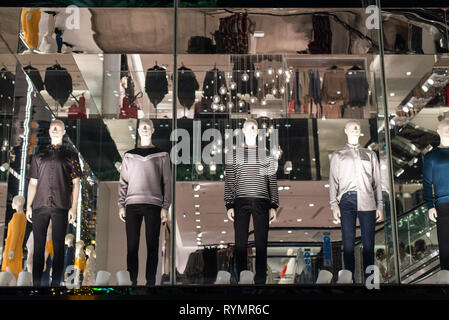 H&M store male mannequins stand in the shop window with a shopping mall interior and reflections in the background. Stock Photo