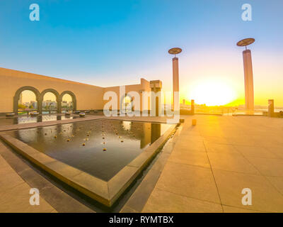 Doha, Qatar - February 20, 2019: Courtyard of Museum of Islamic Art with fountains, benches and arched windows opening view on Doha city center and Stock Photo