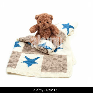 Teddybear sat on knitted blanket on isolated white background Stock Photo