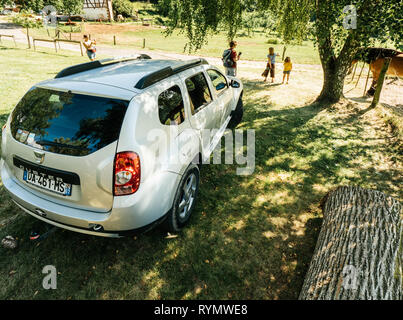 Vosges France - July 8 2018: View from above of French Romanian Dacia Duster SUV parked on the grass lawn in French mountains under a birch tree with people having fun near a horse at farm rancho Stock Photo