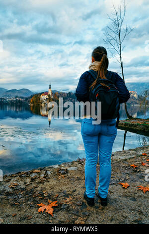 Lady with backpack looking at Bled Lake and Church in Slovenia. Travel in Europe Stock Photo