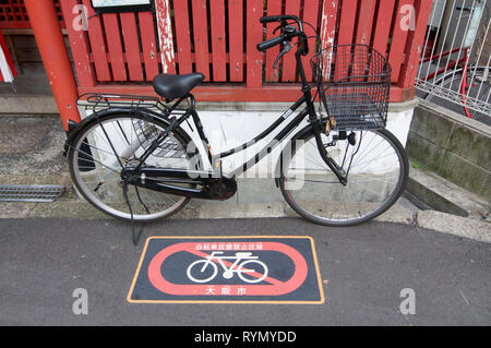 OSAKA, KANSAI, JAPAN - NOVEMBER 8, 2018 : A black bicycle is parked on a parking band sign on a side road near Umeda Station in Osaka, Japan Stock Photo