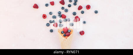 Creative Summer concept composition flat lay top view sweet fresh red raspberries blueberries ice cream waffle cone pink background copy space Templat Stock Photo