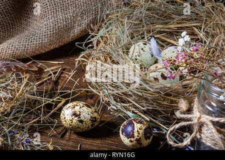 Cute still life with quail eggs. Quail eggs in the nest and on the old wooden table in the barn among vintage items and dried flowers Stock Photo