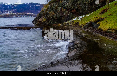 A wave crashes on rock shore. Stock Photo