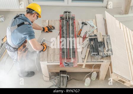 Caucasian Construction Worker and His Workplace. Men Cutting Ceramic Tiles. Stock Photo