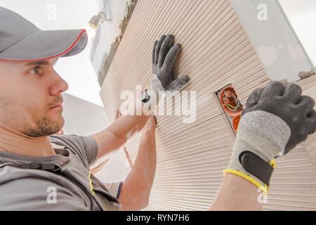 Two Caucasian Workers Installing Large Modern Ceramic Tile Inside Bathroom. Construction and Interior Finishing Concept. Stock Photo