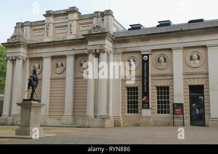 Sir Walter Raleigh statue in front of Pepys Building that has sculpted busts of admirals at the Old Royal Naval College, in Greenwich, London, UK. Stock Photo