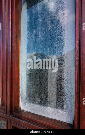 Single glazed door window with condensation forming on the inside of the small door glass Stock Photo