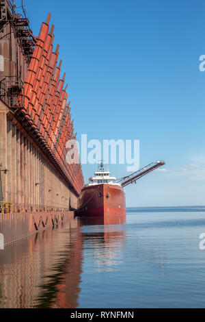 Great lakes freighter at an ore dock on Lake Superior.  Concepts could include shipping, industry, transportation, other.  Copy space in sky. Stock Photo