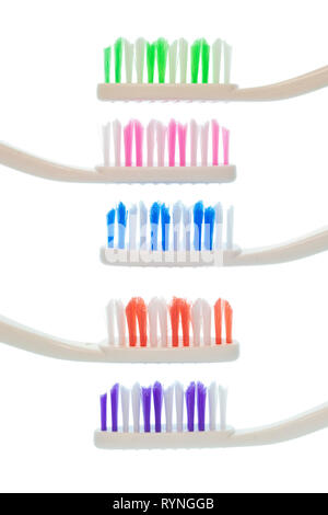 Vertical side view shot of five stacked colorful toothbrushes with white handles isolated on white.  Three of the toothbrushes are laid right to left  Stock Photo