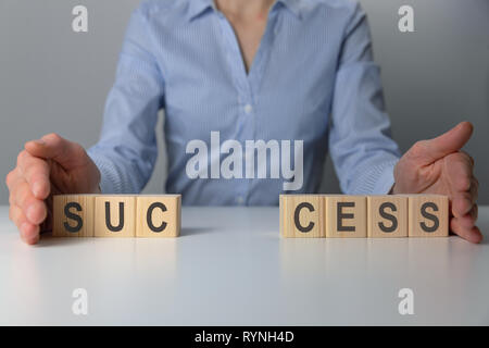 Businesswoman adjusting 'success' word made of wooden blocks. Success word from wooden blocks on desk. Business success Stock Photo