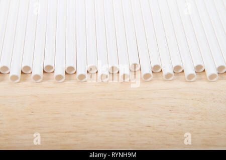Row of paper straws laying on a wood table. Ecologically friendly yet durable paper drinking straws. A ban on plastic straws in restaurants and other  Stock Photo