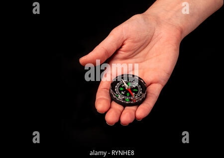 Hand holding the black compass isolated on black background. Stock Photo