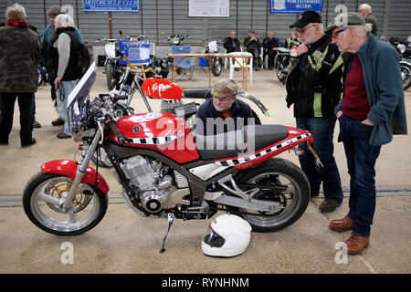 Bike enthusiasts looking at a 1980's red Yamaha SRX600 at a classic vehicle show at Three Counties Showground, Malvern, England, UK Stock Photo