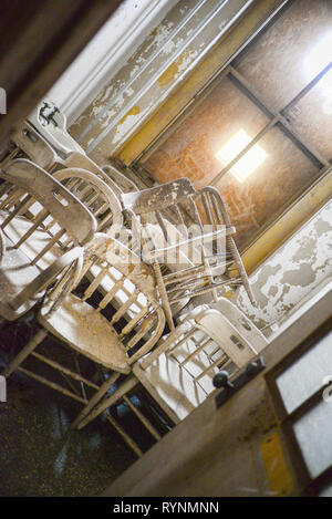 Interior of Decaying Structure Showing Stacked Chairs Stock Photo