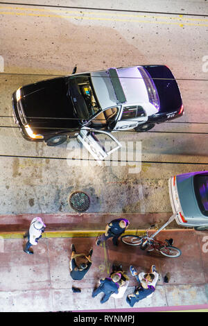 Miami Beach Florida,Ocean Drive,police,car,policeman,officer,uniform,arrest,suspects,sitting on ground,public safety,protect,working,work,employee wor Stock Photo