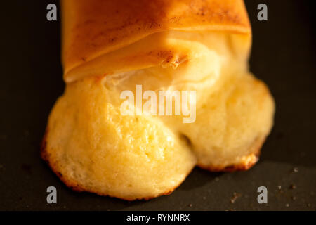 Baked puff pastry close up. Melted cheese out of baked cooked flaky puff pastry cheese bite. Stock Photo