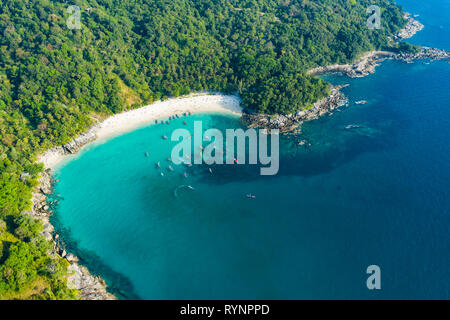 View from above, stunning aerial view of a beautiful tropical beach with white sand and turquoise clear water, long-tail boats and people sunbathing Stock Photo