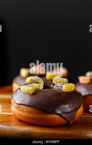 Concept of cooking, baking and food - close-up. Chocolate coated donuts decorated with marmalade. Appetizing still life. Stock Photo