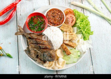 Fried pomfret fish and rice, popular traditional Malay or Indonesian local food. Flat lay top down overhead view. Stock Photo