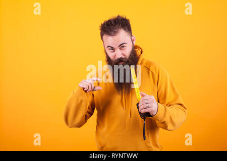 Funny bearded man showing dimension on roulette over yellow background.Handyman. Constructor Stock Photo