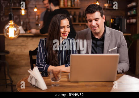 Two programmers are working together on a project in a coffee shop from their laptop. Modern business. Business meeting. Stock Photo