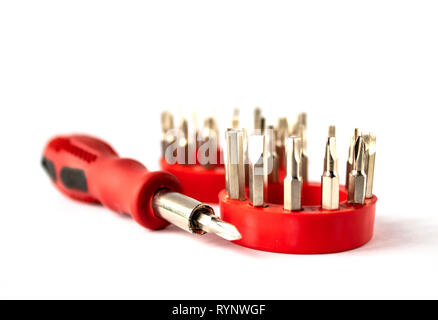 Screwdriver with red handle, set of screwdriver heads (bits) for tools, close-up, selective focus, on a white background. Stock Photo