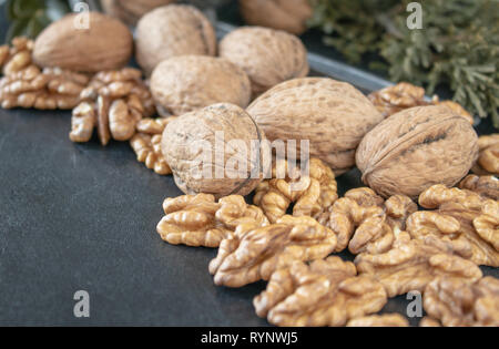 Ripe whole walnuts and peeled walnut kernels against a black background. Stock Photo