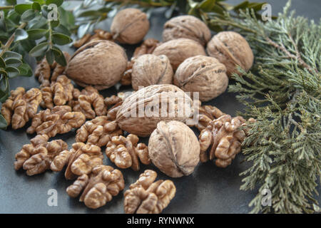 Ripe whole walnuts and peeled walnut kernels against a black background. Stock Photo