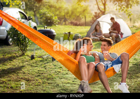Love couple enjoy in hammock chair with beer relaxing in nature Stock Photo