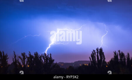 Night lightning storm over city in blue dramatic lighting Stock Photo