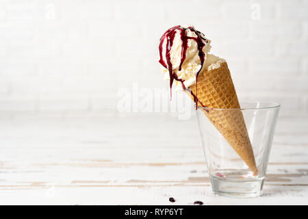 Vanilla ice cream scoop in cone with cherry sauce Stock Photo