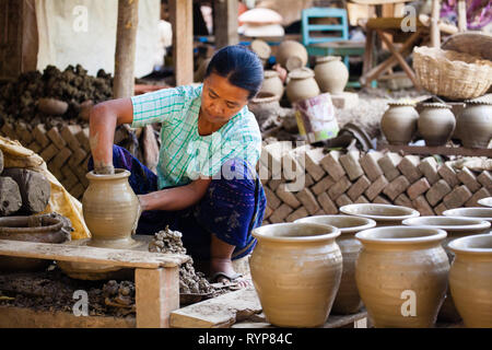 A female worker makes clay pots at Yandabo pottery village in Myanmar Stock Photo