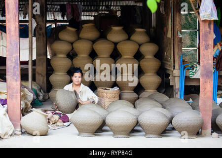 A female worker makes clay pots at Yandabo pottery village in Myanmar Stock Photo